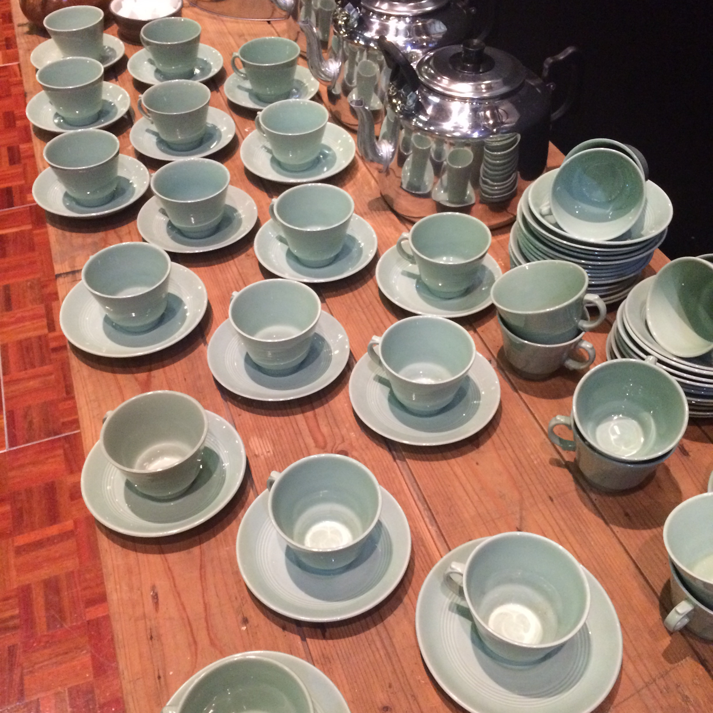 A table covered in teal green cups and saucers
